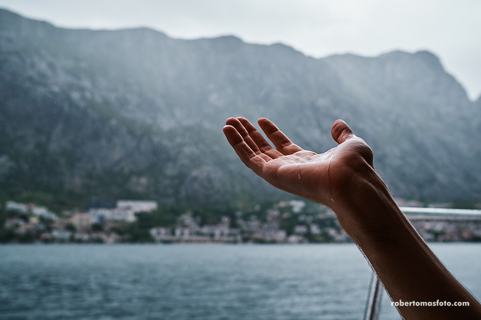 Una mano bajo la lluvia. Vista de Perast desde un barco en la bahía de Kotor