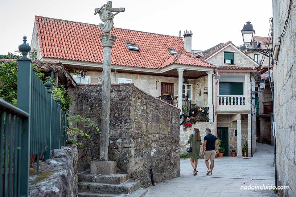 Una pareja pasea junto a un cruceiro de Combarro (Galicia)