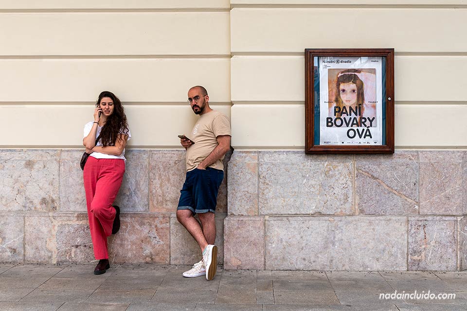 Dos personas con el teléfono móvil junto al Teatro Estatal - Calle Ovocný de Praga (República Checa)