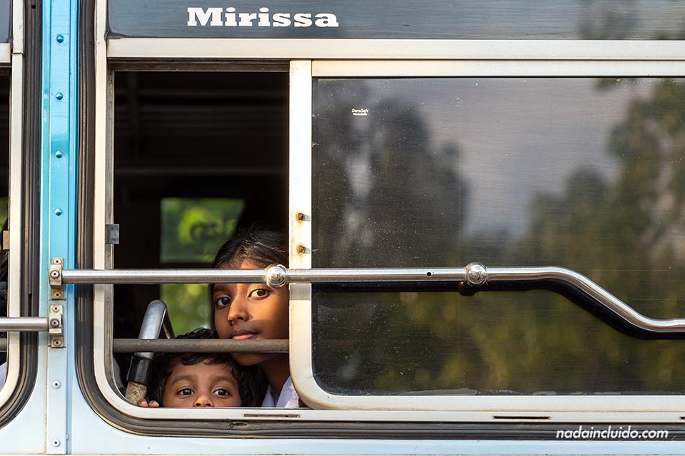 Niños asomándose por la ventanilla de un autobús junto al templo Bodhiya - Calle Nilwala By pass de Matara (Sri Lanka)